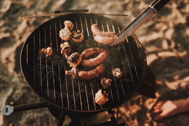 Conceito de festa de praia. Homem Grelha Salsichas De Churrasco.