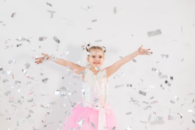 Conceito de festa, feriados, aniversário, ano novo e celebração - linda criança jogando confete.