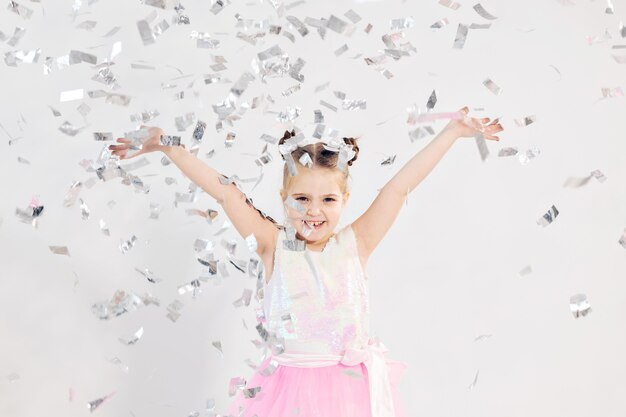 Conceito de festa, feriados, aniversário, ano novo e celebração - linda criança jogando confete.
