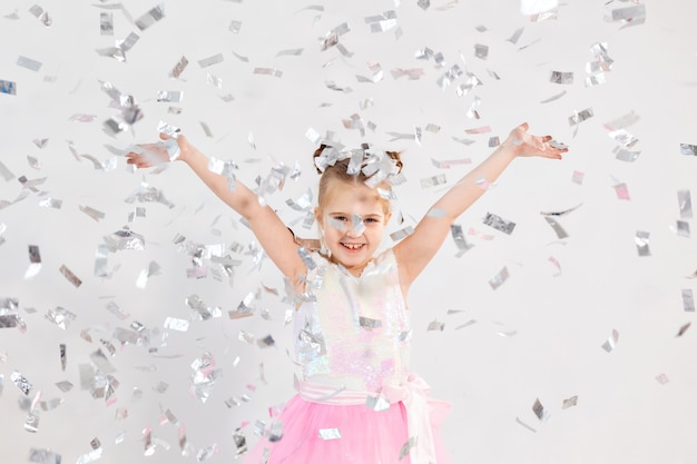 Conceito de festa, feriados, aniversário, ano novo e celebração - linda criança jogando confete.