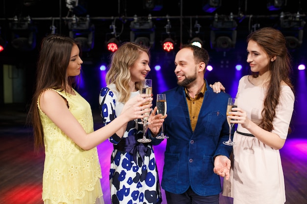 Conceito de festa, feriados, celebração, vida noturna e pessoas - amigos sorridentes com taças de champanhe no clube