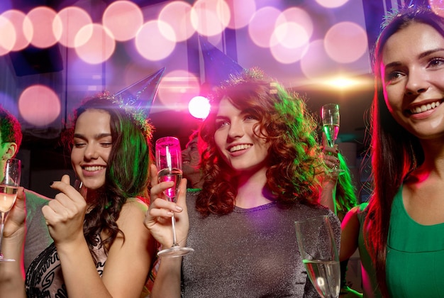 Conceito de festa, feriados, celebração, vida noturna e pessoas - amigos sorridentes com taças de champanhe no clube