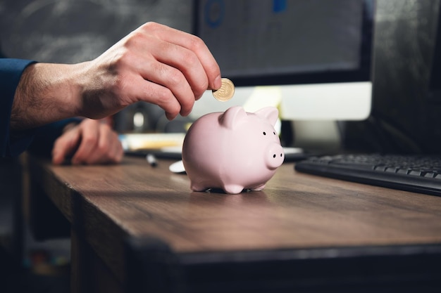 Conceito de finanças Homem colocando dinheiro no cofrinho