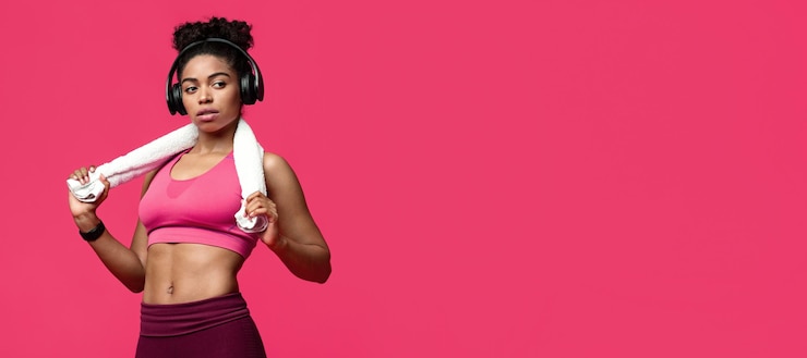 Foto conceito de fitness de ginásio atraente garota negra esportiva com toalha e fones de ouvido olhando para o espaço de cópia sobre