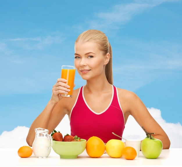 conceito de fitness, dieta e saúde - jovem sorridente com café da manhã saudável e bebendo suco de laranja