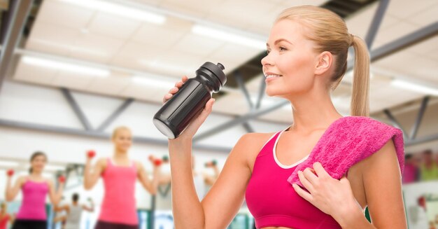 conceito de fitness e dieta - mulher desportiva com garrafa e toalha especial de esportista