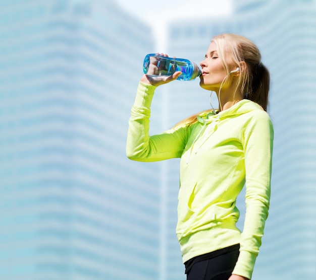 conceito de fitness e estilo de vida - mulher bebendo água depois de praticar esportes ao ar livre