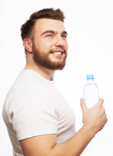 conceito de fitness e estilo de vida sorridente homem musculoso esportivo vestindo camisa branca com garrafa de água isolado em branco