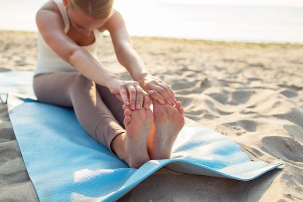 conceito de fitness, esporte, pessoas e estilo de vida - close-up de mulher fazendo exercícios de ioga no tapete ao ar livre