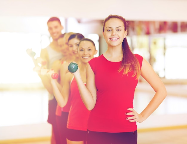conceito de fitness, esporte, treinamento, ginástica e estilo de vida - grupo de pessoas sorridentes levantando halteres na academia