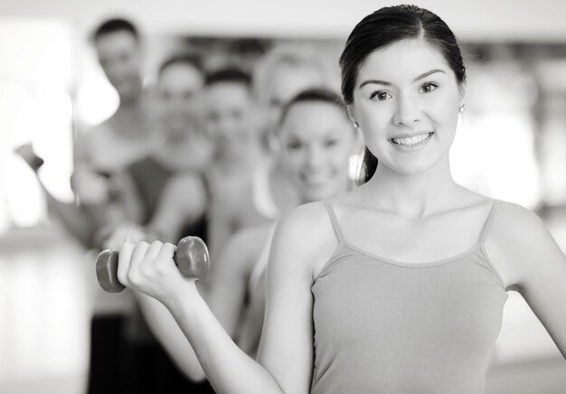 conceito de fitness, esporte, treinamento, ginástica e estilo de vida - grupo de pessoas sorridentes levantando halteres na academia