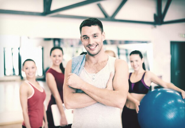 conceito de fitness, esporte, treinamento, ginástica e estilo de vida - homem sorridente em frente a um grupo de pessoas na academia