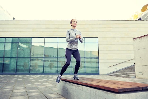 conceito de fitness, esporte, treinamento, pessoas e estilo de vida - jovem fazendo exercício de passo no banco da rua da cidade