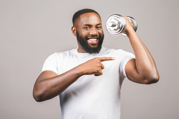Conceito de fitness. retrato de um homem negro afro-americano feliz com os pesos isolados sobre o fundo cinzento.