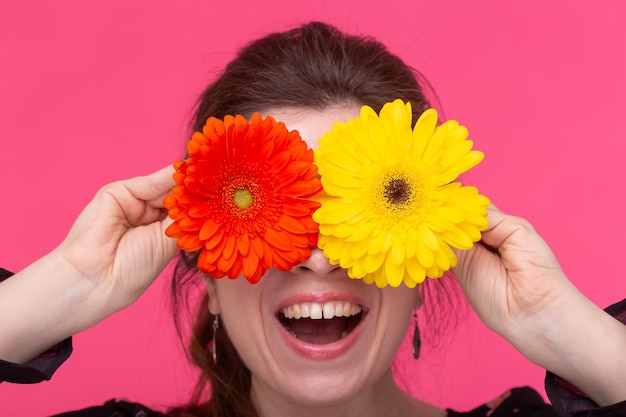 Conceito de flores, emoções e pessoas - a mulher fechou os olhos com gerberas na parede rosa