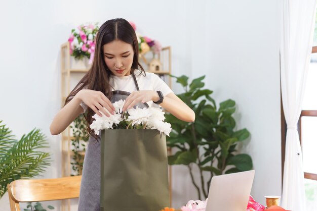 Conceito de florista Florista feminina organizando buquê de flores de crisântemo em sacola de compras na loja