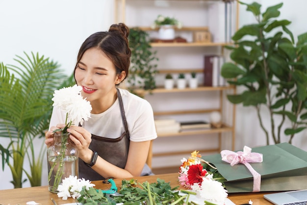 Conceito de florista Sorriso de florista feminina e cheiros de crisântemos brancos em vaso com felicidade