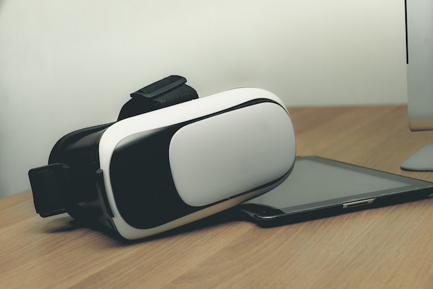 Foto conceito de fone de ouvido de realidade virtual de realidade virtual vr e tablet na mesa de madeira