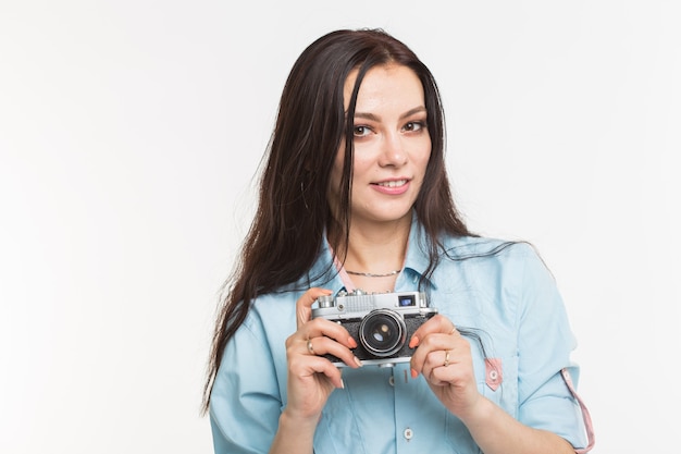 Conceito de fotógrafo, passatempo e pessoas - jovem morena com câmera retro em fundo branco.