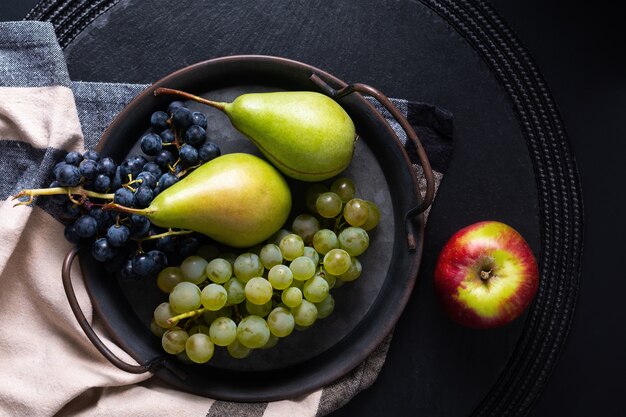 Conceito de fruta natureza morta pêra e uva em bandeja de ferro vintage com espaço de cópia