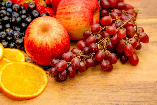Conceito de frutas frescas Frutas saudáveis consistem em uvas maçã laranja e baga em fundo de madeira