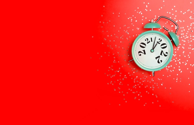 Conceito de fundo de banner de ano novo muda para um despertador em um fundo vermelho com festivo.