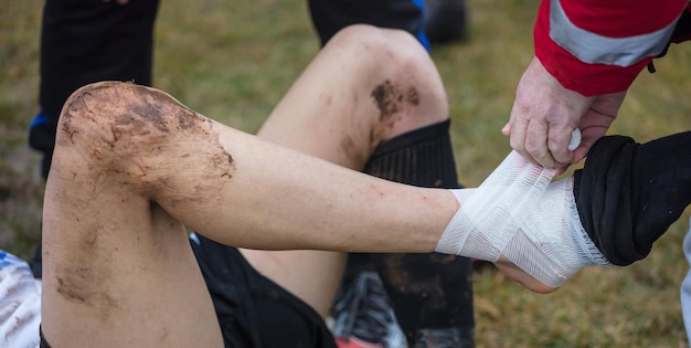 Conceito de futebol de futebol jogador de futebol ferido deitado no campo com dor no tornozelo visão de perto do fundo desfocado