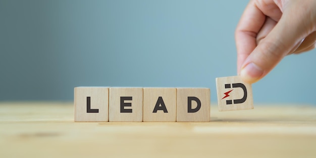 Conceito de geração de leads, cliente líder e cultivo Estratégia de marketing de entrada Mão segura cubos de madeira com ímã atrai ícones de clientes em pé com texto LEAD em fundo cinza espaço de cópia