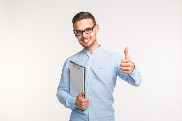 Conceito de gesto de aprovação e correção - homem bonito feliz aparecendo o polegar na parede branca.