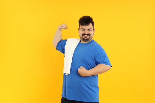 Conceito de gordo de perda de peso com toalha em fundo amarelo