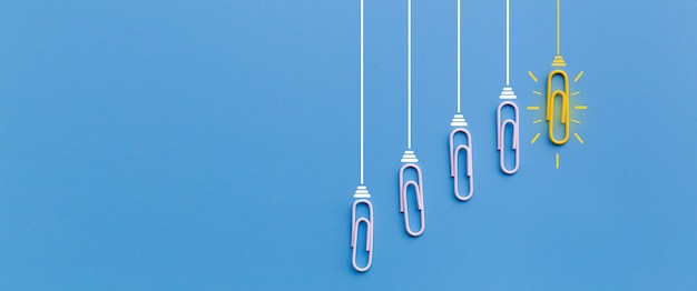 Foto conceito de grandes idéias com clipe de papel pensando criatividade lâmpada sobre fundo azul