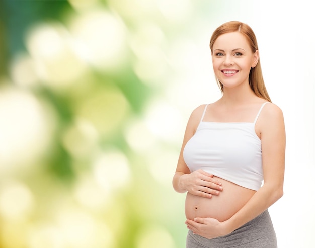 conceito de gravidez, maternidade e felicidade - feliz futura mãe tocando sua barriga