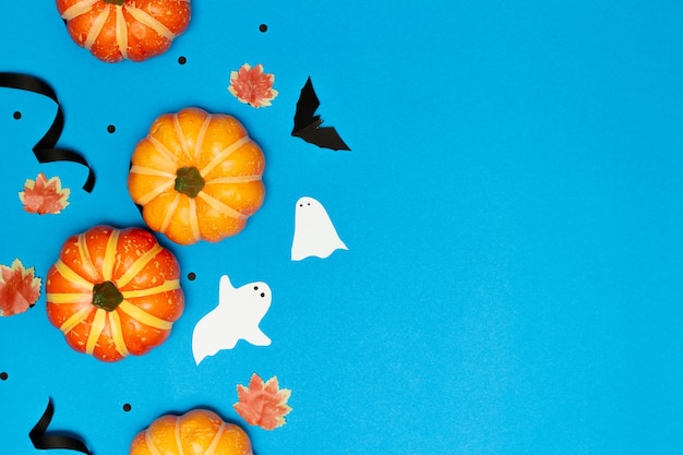 Conceito de Halloween Abóbora de sorriso assustador com fantasma e morcego preto voador sobre fundo azul claro