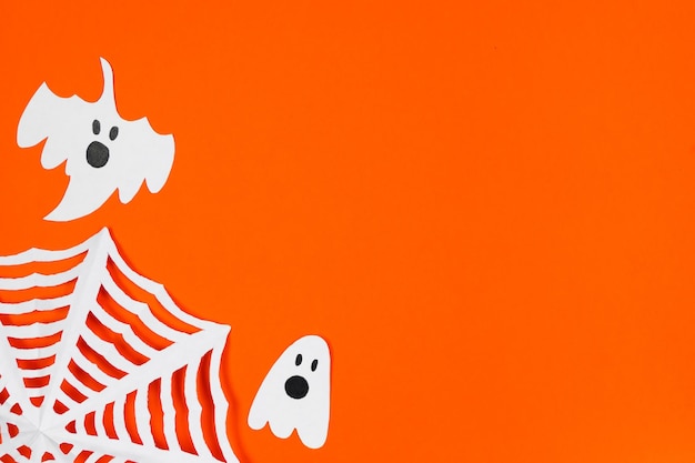 Conceito de Halloween Fantasmas de papel de decorações festivas e teia de aranha em fundo laranja
