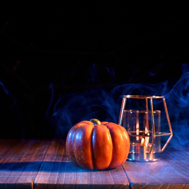 Conceito de Halloween Lanterna de abóbora laranja em uma mesa de madeira escura com fumaça de cor dupla ao redor do truque ou deleite de fundo perto