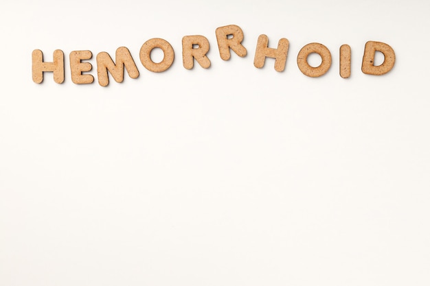 Conceito de hemorróidas com letras de madeira em fundo branco