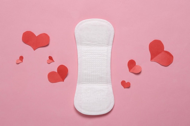 Foto conceito de higiene feminina almofadas de mulher menstrual para proteção de higiene em dias críticos com corações em fundo rosa pastel