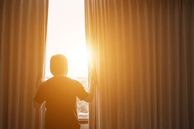 Conceito de homem e esperança. homem abrindo as cortinas da janela