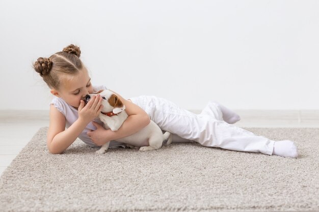 Conceito de infância, animais de estimação e cães - menina criança posando no chão com o cachorrinho.