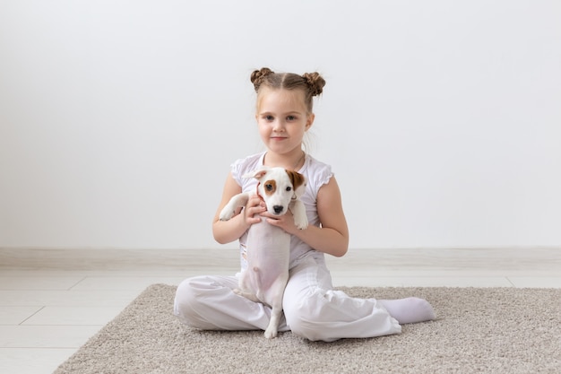 Conceito de infância, animais de estimação e cães - menina criança posando no chão com o cachorrinho.