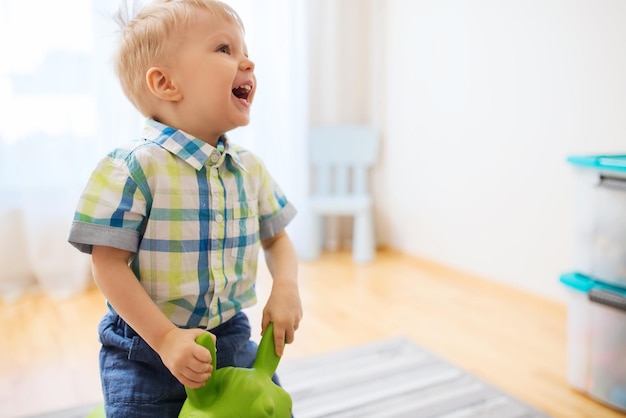 conceito de infância, brinquedos e pessoas - bebezinho feliz brincando com cavalo de brinquedo em casa