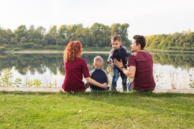 Conceito de infância e natureza - família com filhos pequenos sentados na grama verde.