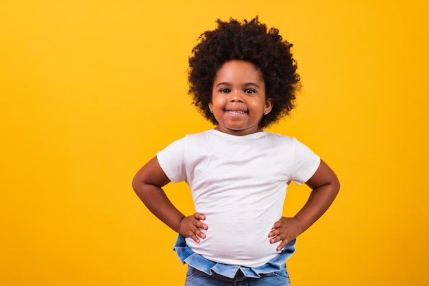 Conceito de infância e pessoas - feliz garotinha afro-americana sobre fundo amarelo. menina negra com cabelo preto poderoso sorrindo.