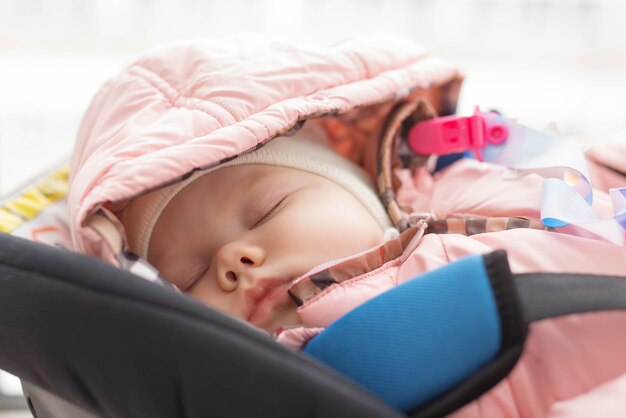 Conceito de infância e segurança - menina bebê dormindo na cadeirinha infantil.