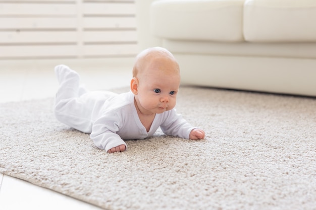 Conceito de infância, infância e pessoas - menino ou menina rastejando no chão em casa.