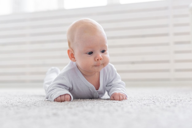 Conceito de infância, infância e pessoas - menino ou menina rastejando no chão em casa.