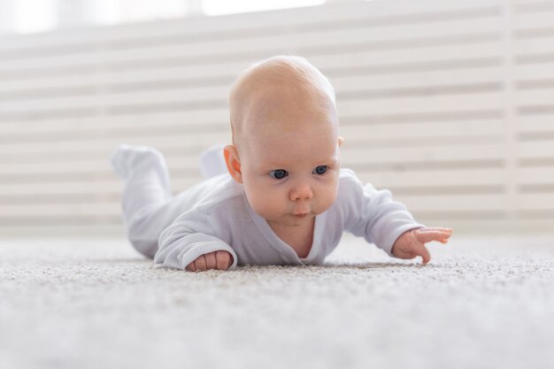 Conceito de infância, infância e pessoas - menino ou menina rastejando no chão em casa.