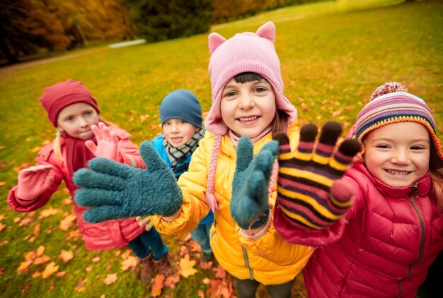 conceito de infância, lazer, amizade e pessoas - grupo de crianças felizes acenando as mãos no parque outono
