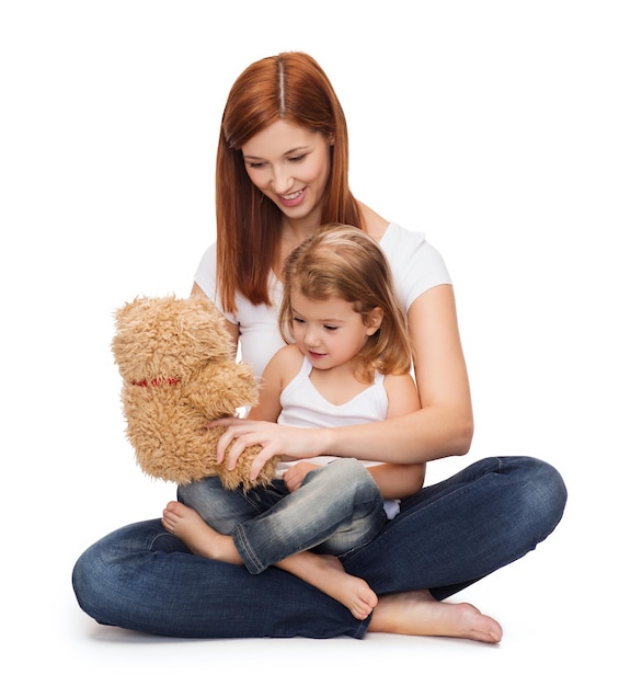 conceito de infância, paternidade e relacionamento - mãe feliz com adorável garotinha e ursinho de pelúcia