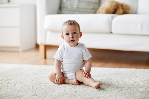 conceito de infância, primeira infância e pessoas - menino ou menina feliz sentado no chão em casa